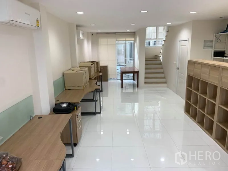 Home Office for rent or sale in Bang Na, Bangkok - Open-plan office area with long wooden desks, storage units and recessed lighting.