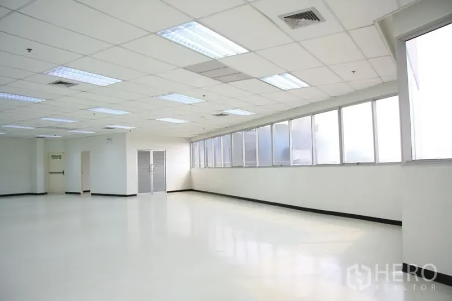 Office Space for rent in Chatuchak, Bangkok - Open workspace with polished floors, frosted windows, exit doors, and suspended ceiling.