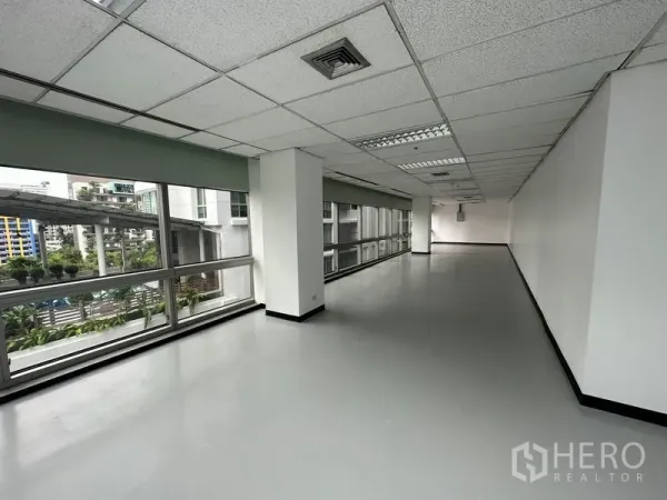 Office Space for rent - Narrow office zone with columns and continuous glazing overlooking greenery and towers.