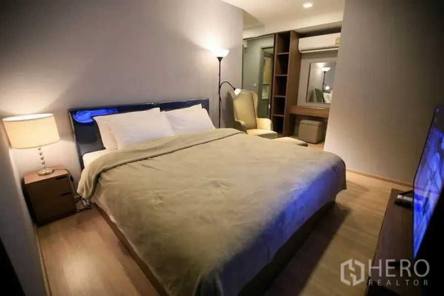 Condominium for rent or sale in Watthana, Bangkok - Cozy master bedroom with king bed, wood floors, soft lighting and built-in wardrobe near BTS Ekkamai.