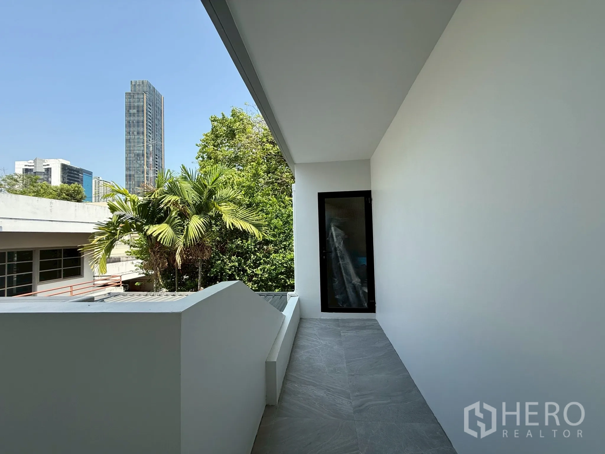 โฮมออฟฟิศ for rent in Watthana, Bangkok - ระเบียงทางเดินเห็นวิวสกายไลน์และต้นปาล์ม