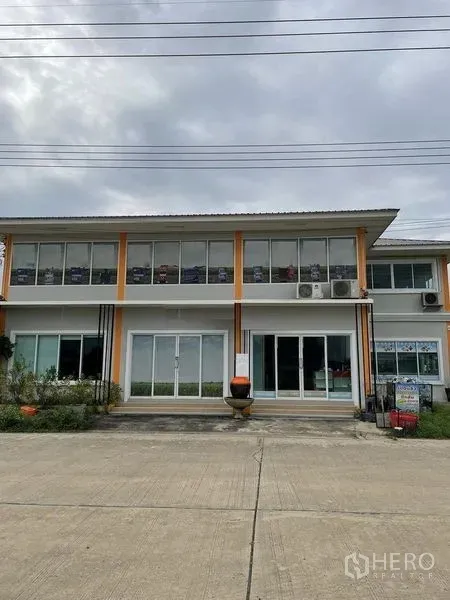 Warehouse for rent or sale in Pathum Thani - Two-story office building with glass facade and exterior air-conditioning units.