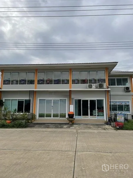 Warehouse for rent or sale in Pathum Thani - Two-story office building with glass facade and exterior air-conditioning units.