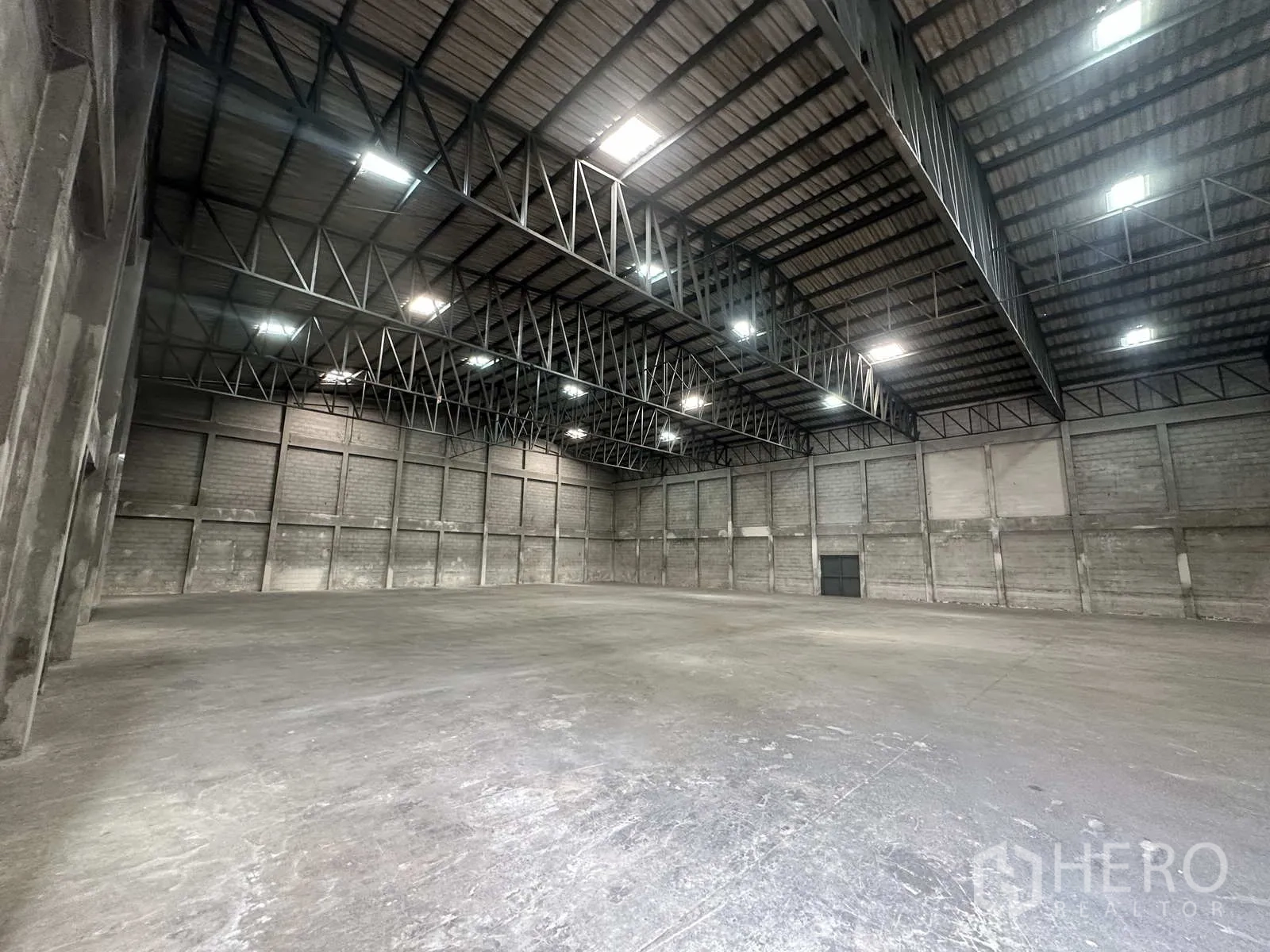 Warehouse for rent in Phra Nakhon Si Ayutthaya - Smooth concrete floor beneath illuminated roof trusses in the warehouse.