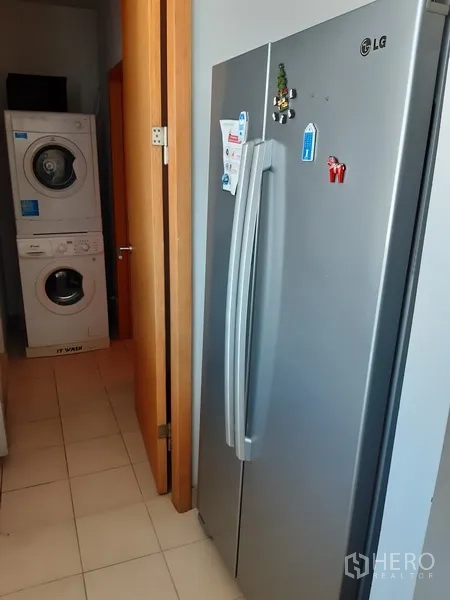 Condominium for rent in Khlong Toei, Bangkok - Utility zone with double-door refrigerator and stacked washer and dryer.