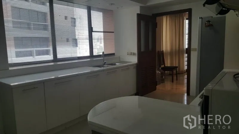 Condominium for rent in Khlong Toei, Bangkok - Bright secondary kitchen area with long countertop, sink, and wide windows.