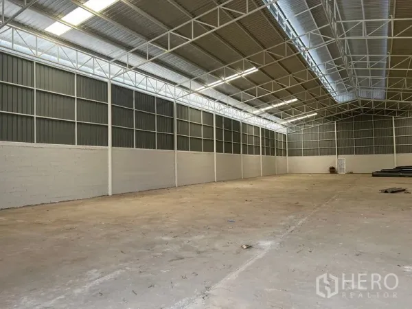Warehouse for rent in Min Buri, Bangkok - Side view of warehouse showing ventilated metal panels and bright natural lighting.