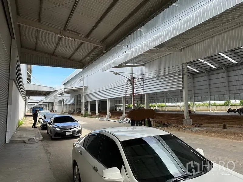 Warehouse for rent in Wang Noi, Phra Nakhon Si Ayutthaya - Long canopied driveway between warehouse bays with roller shutters and parking.