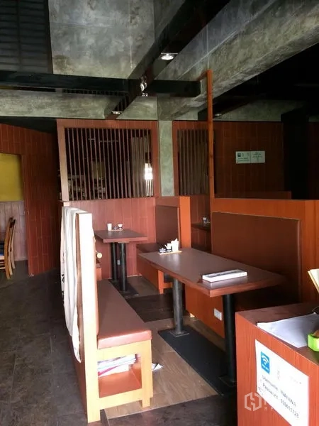 Retail Space for rent in Khlong Toei, Bangkok - Built-in booth seating with wooden partitions and a concrete ceiling inside the retail unit.