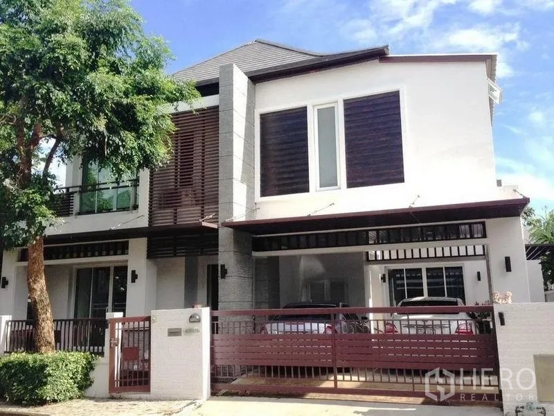 Detached House for rent or sale in Prawet, Bangkok - Front facade with gated driveway and covered carport for two cars.
