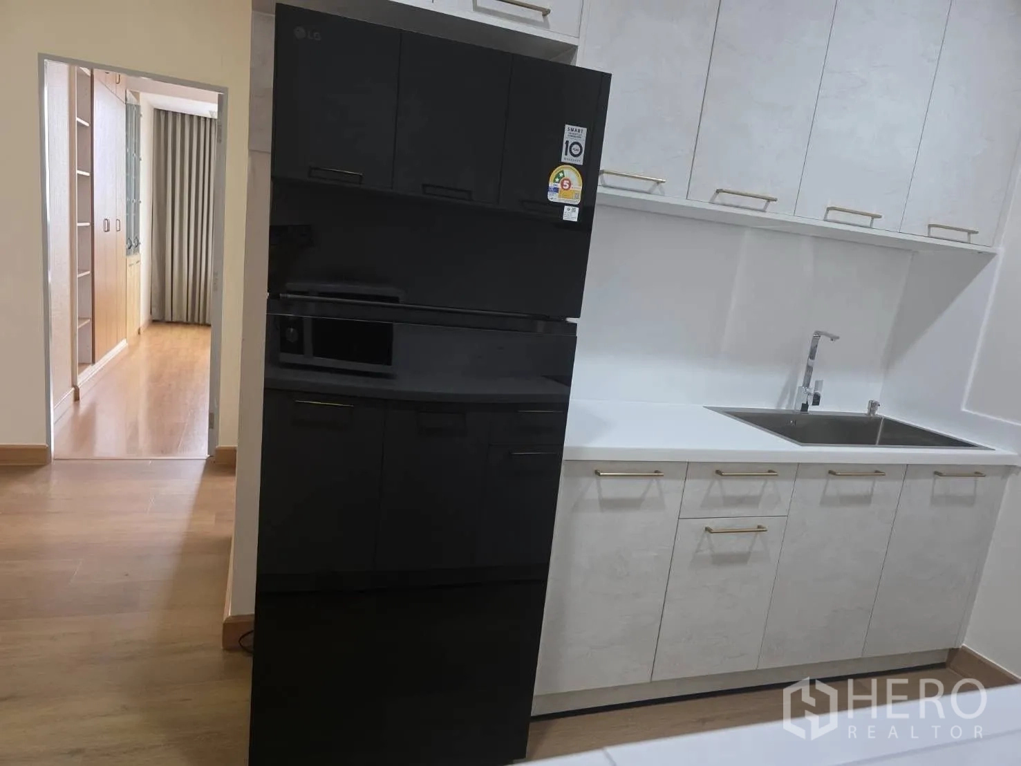 Condominium for rent in Khlong Toei, Bangkok - Kitchen close-up showing deep sink, cabinets and large refrigerator.