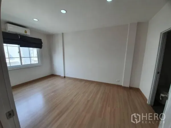 Townhouse for rent in Bang Na, Bangkok - Spacious bedroom with wood laminate floors, window blinds, air conditioner and ensuite access.