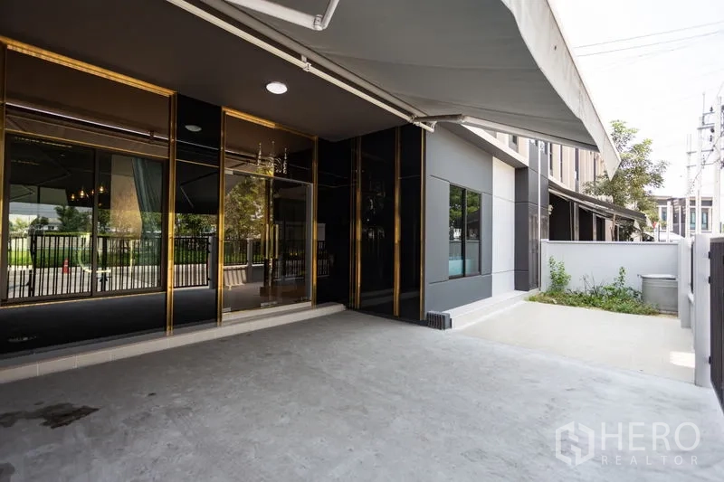 Townhouse for rent in Bang Phli, Samut Prakan - Covered carport and front terrace with a retractable awning and black-gold facade.