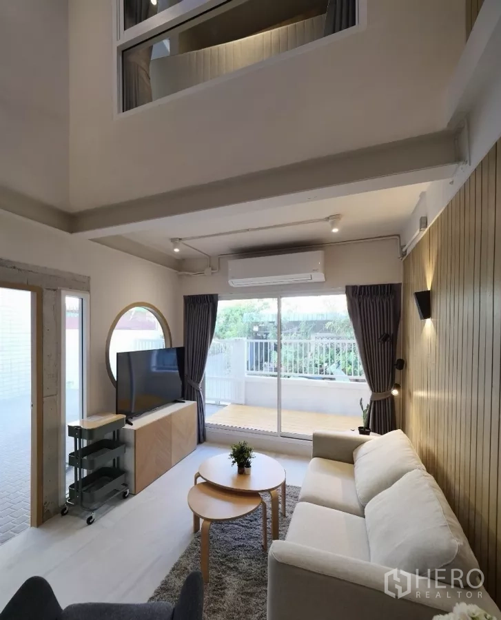 Townhouse for rent or sale in Watthana, Bangkok - Bright living area with large glass doors opening to the front deck.
