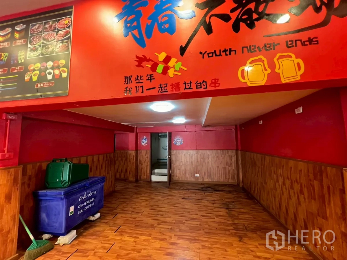 Shophouse for rent in Watthana, Bangkok - Ground-floor corridor with wood flooring and bold red signage.
