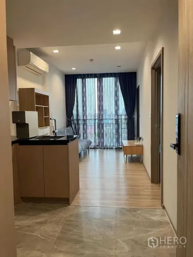 Condominium for sale in Watthana, Bangkok - Entrance view to living area and kitchenette leading out to a balcony.