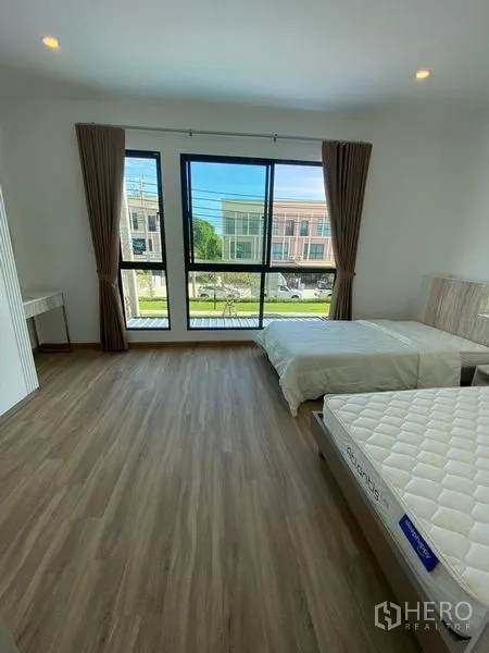 Townhouse for rent in Bang Kapi, Bangkok - Bright bedroom with twin beds and floor-to-ceiling windows overlooking the neighborhood.