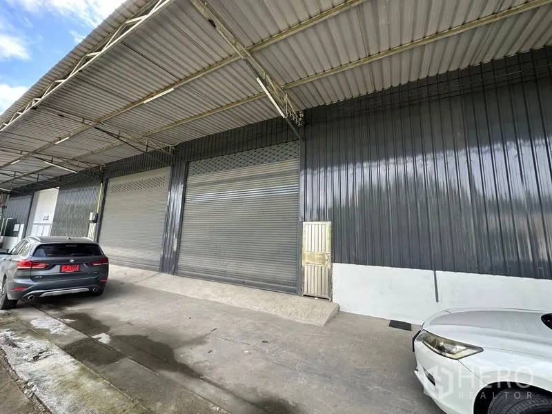 Warehouse for rent in Khlong Luang, Pathum Thani - Close view of loading dock with metal roll-up shutters beneath the covered canopy.