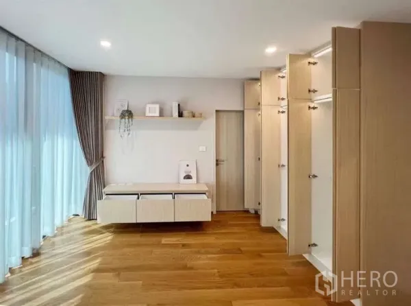 Townhouse for rent or sale in Saphan Sung, Bangkok - Bright bedroom with open wall-to-wall wardrobes, floating console, sheer curtains and timber flooring.