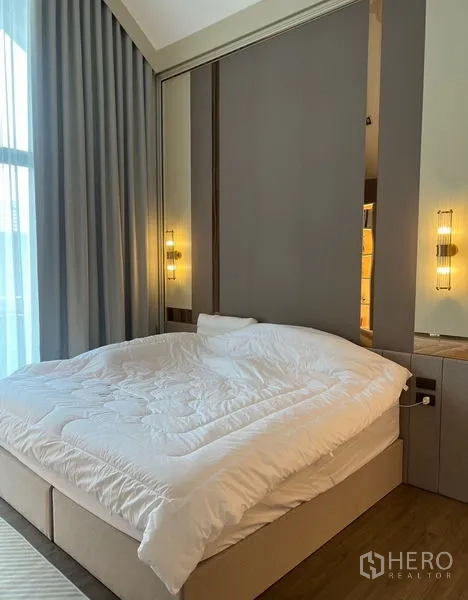 Detached House for sale in Bang Kapi, Bangkok - Master bedroom with high ceiling, upholstered bed and warm bedside lighting.