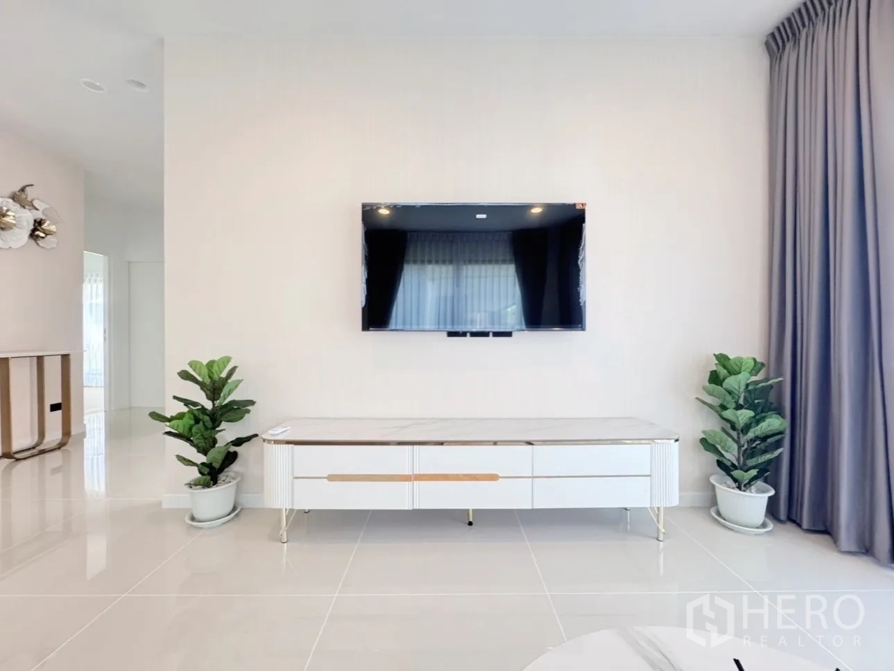 Detached House for rent or sale in Bang Kapi, Bangkok - TV console wall with potted plants and a flat-screen in a light-filled lounge.