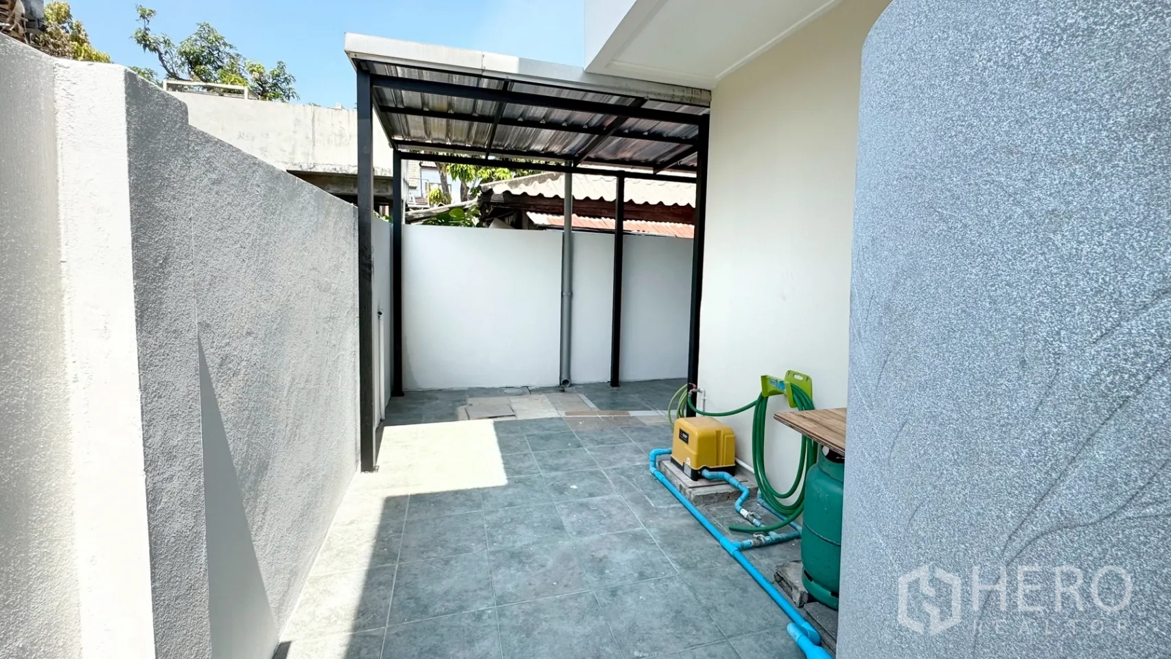 บ้านเดี่ยว for rent in Suan Luang, Bangkok - ลานเอนกประสงค์ด้านหลังมีหลังคาบางส่วน กำแพงสูง พร้อมปั๊มน้ำและพื้นที่วางถังแก๊ส