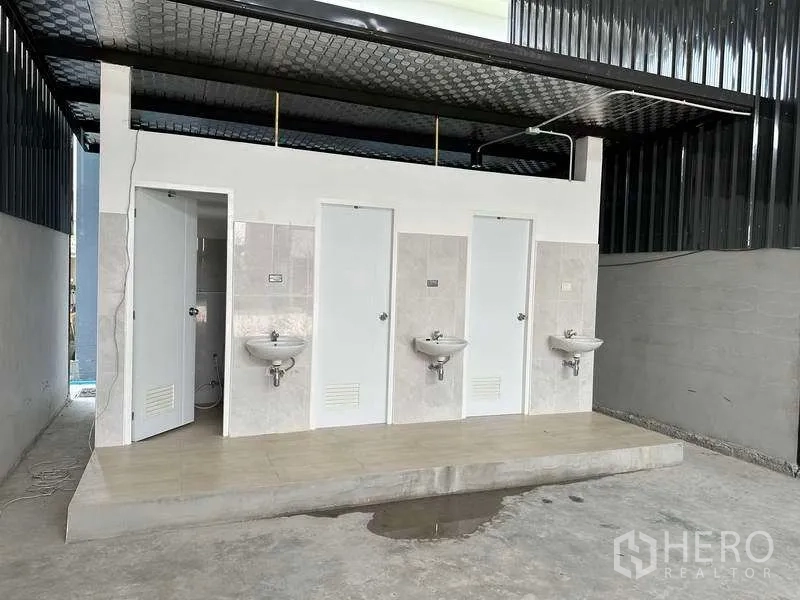 Warehouse for rent in Khlong Sam Wa, Bangkok - Separate restroom block inside the warehouse with three white doors and wall-mounted sinks.