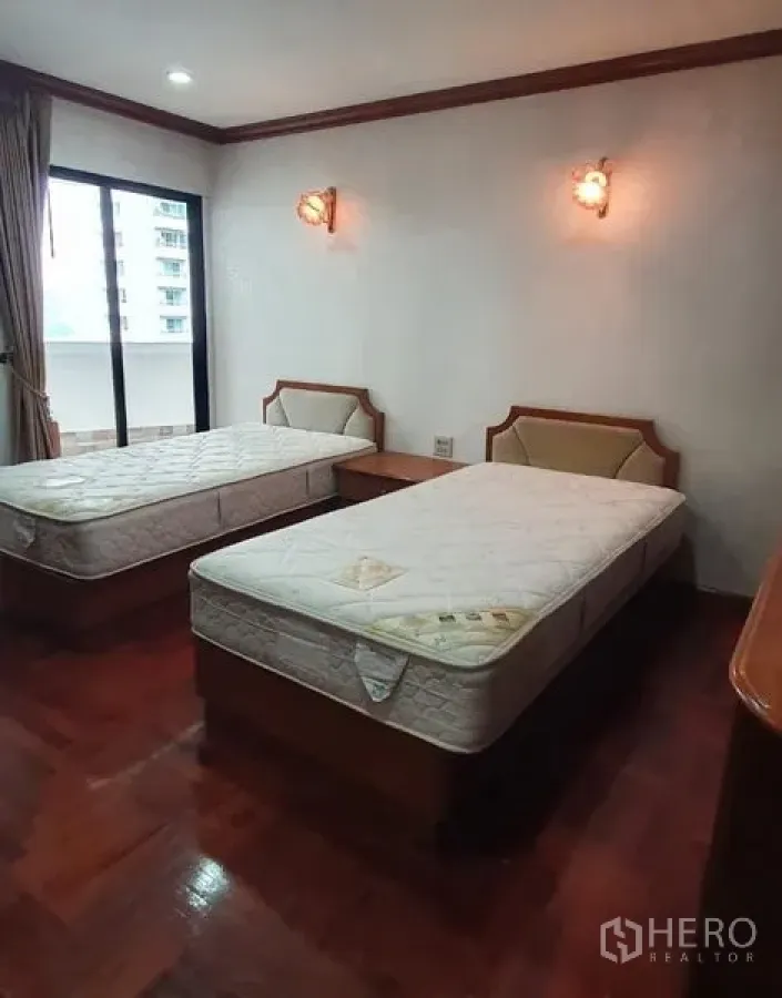 Condominium for rent in Khlong Toei, Bangkok - Twin-bed bedroom with hardwood floors and balcony access in President Park condo.