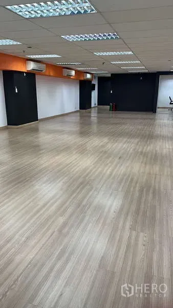 Office Space for rent - Open workspace with orange accent soffit, multiple wall air conditioners and wood floors.