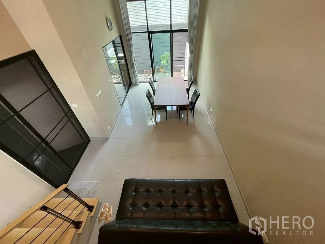 Townhouse for rent in Suan Luang, Bangkok - Double-height living and dining area with floor-to-ceiling windows and glossy tile floors in a modern Suan Luang townhouse.