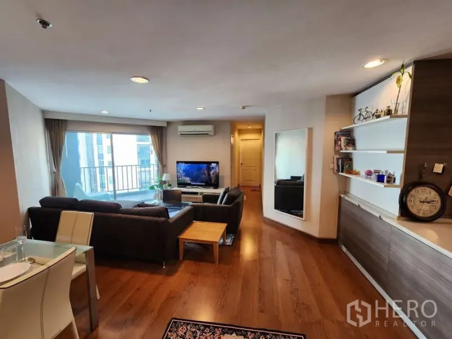 Condominium for rent in Huai Khwang, Bangkok - Wide view of airy lounge with balcony access, built-in shelving and recessed lighting.