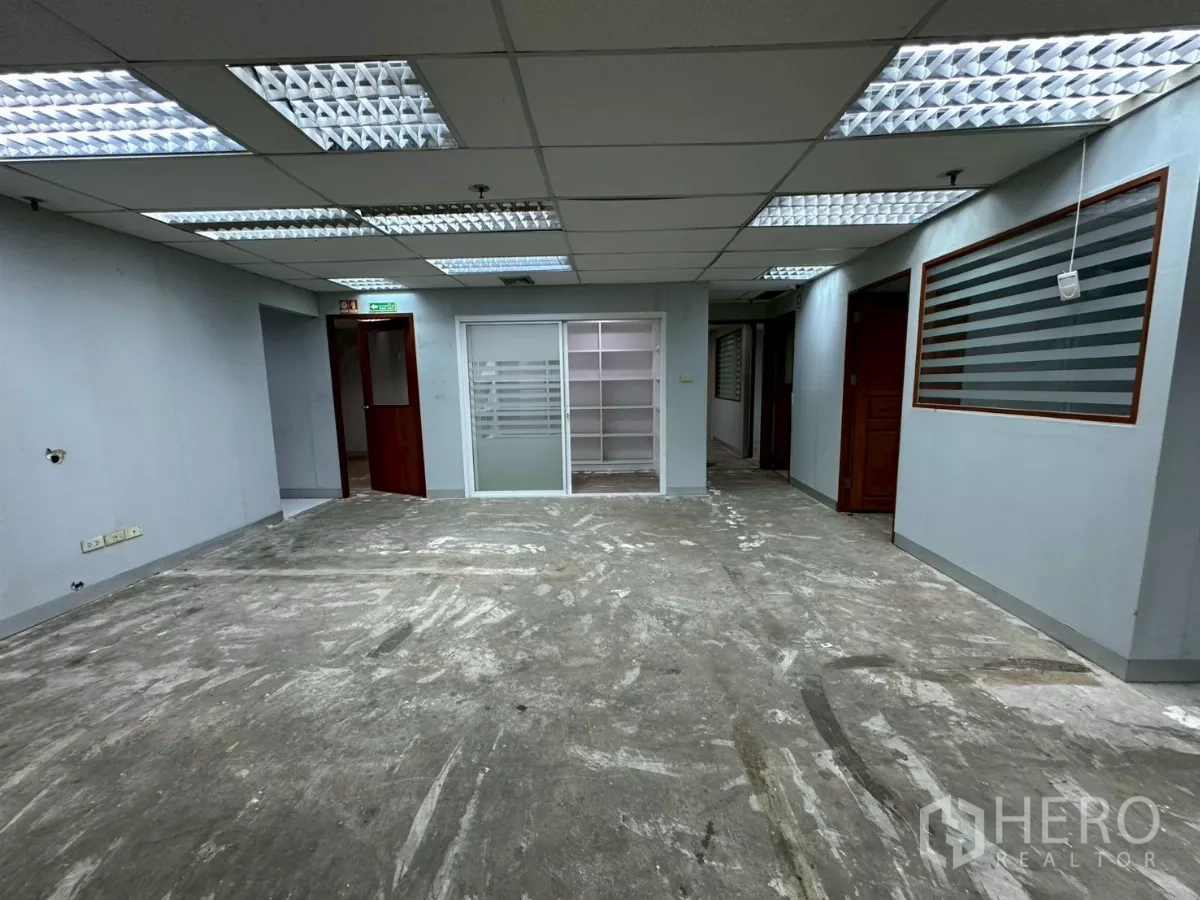 Office Space for rent in Khlong Toei, Bangkok - Corridor and open area with sliding glass entry, built-in shelving and multiple doors.