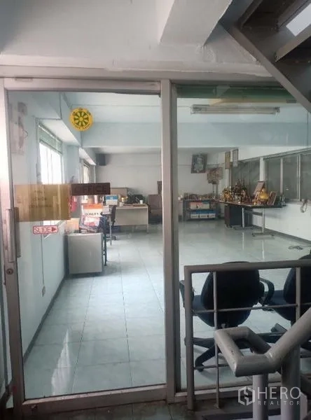Factory for sale in Khlong Luang, Pathum Thani - Glass-enclosed ground floor office with tiled floors and desks.