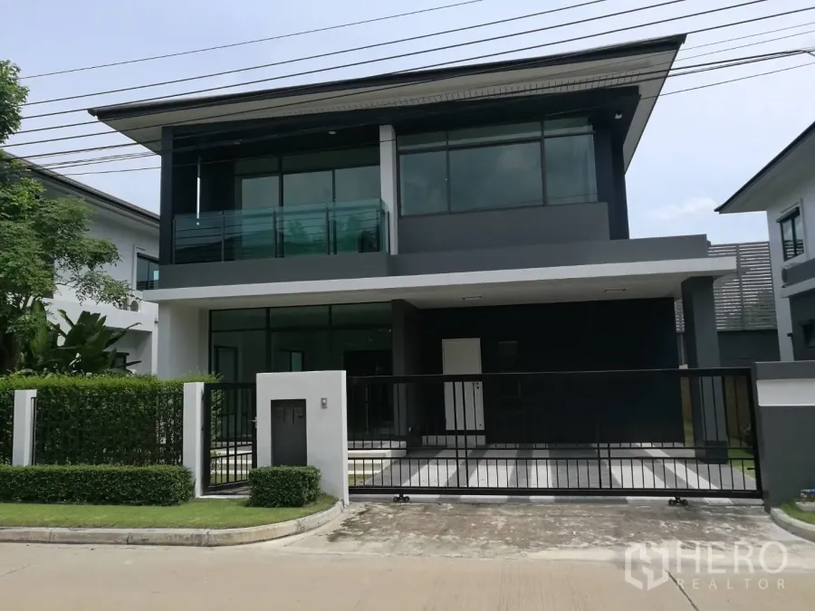 Detached House for rent in Bang Kapi, Bangkok - Modern two-storey detached house with gated driveway, balcony and large windows in a landscaped estate.