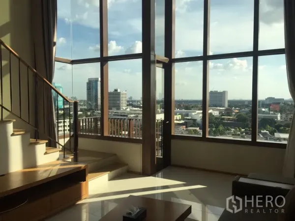 Condominium for rent in Khlong Toei, Bangkok - Corner glass walls with balcony door and panoramic skyline view beside the stair landing.