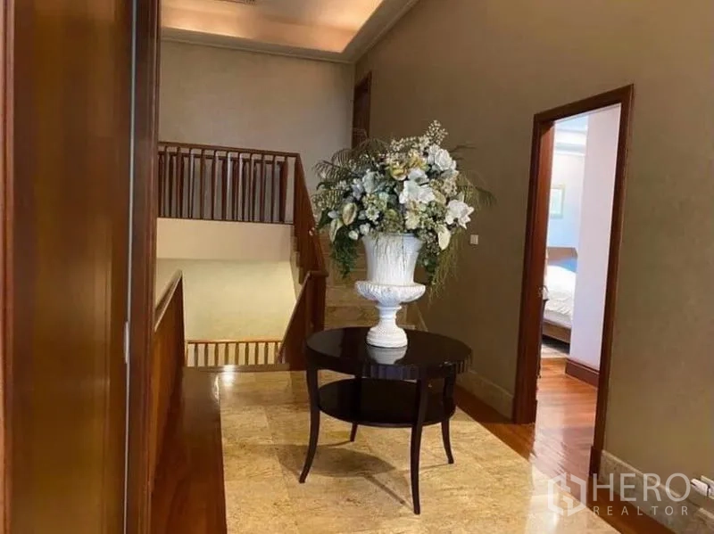 Detached House for rent in Khlong Toei, Bangkok - Upper landing hallway with staircase, marble floor and a decorative flower arrangement.