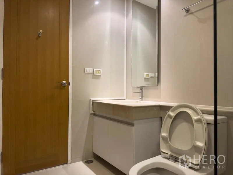 Condominium for rent or sale in Pathum Wan, Bangkok - Clean bathroom with long vanity, large mirror and white toilet.