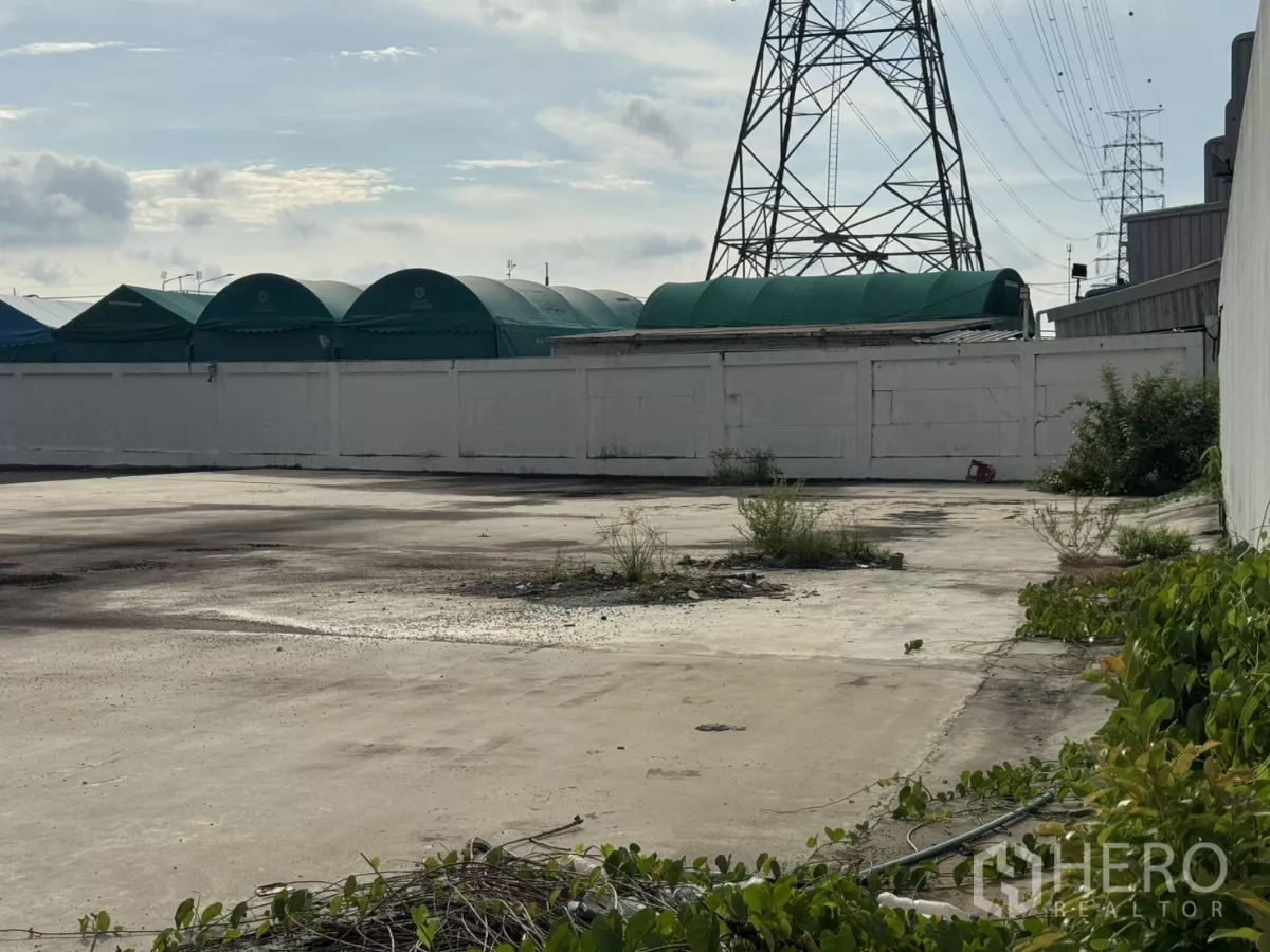 Factory for rent or sale in Bang Phli, Samut Prakan - Open yard beside power pylons and green tented structures.