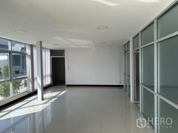 Warehouse for rent in Samut Prakan - Bright glass-partitioned office room with tiled floors and large windows.
