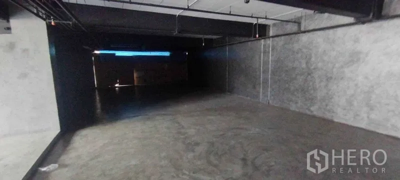 Office Space for rent in Chatuchak, Bangkok - Long raw-finish office area with smooth concrete flooring, cement walls and exposed conduits.