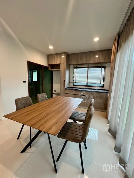 Detached House for rent in Bang Kapi, Bangkok - Dining area with wood table for four beside pantry cabinets and window.