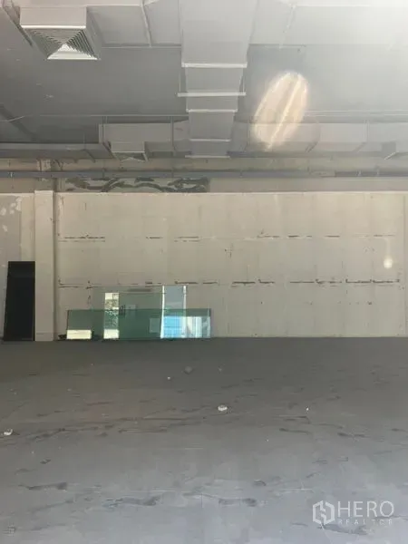 Retail Space for rent in Khlong Toei, Bangkok - Wide open retail area showing exposed ducting, blank feature wall and glass panels on the floor, ready for tenant fit-out.