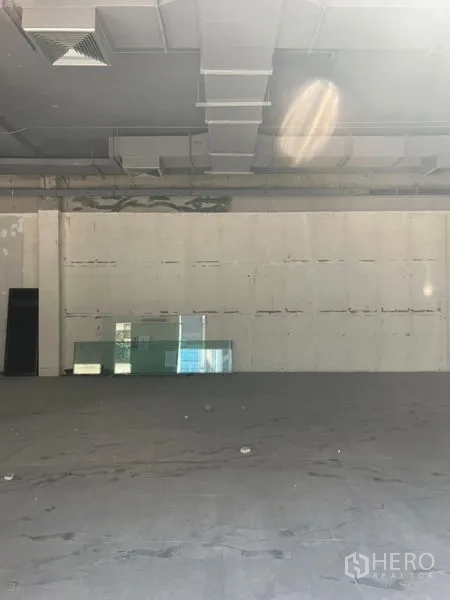 Retail Space for rent in Khlong Toei, Bangkok - Wide open retail area showing exposed ducting, blank feature wall and glass panels on the floor, ready for tenant fit-out.