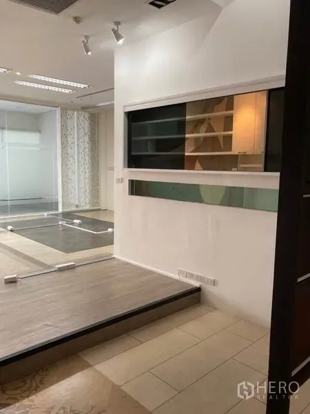 Office Space for rent in Khlong Toei, Bangkok - Raised platform zone with service window and a glass-walled meeting room ahead.
