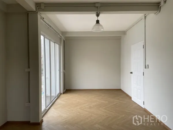 Detached House for rent or sale in Din Daeng, Bangkok - Spacious room with large sliding windows, white door and light herringbone flooring.