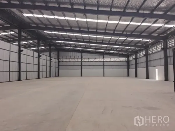 Factory for rent in Chon Buri - Spacious warehouse interior with high steel roof and polished concrete floor.