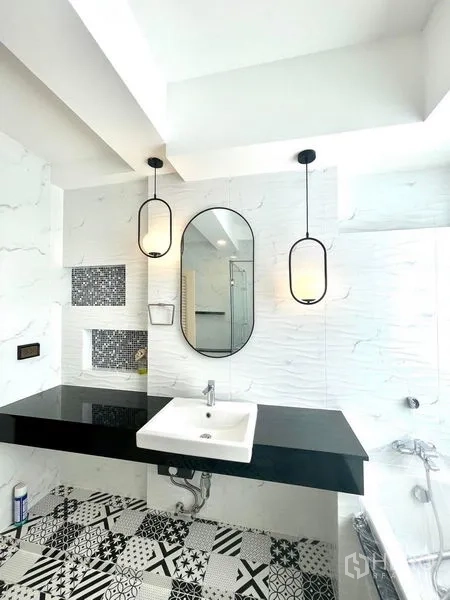 Townhouse for rent in Khlong Toei, Bangkok - Contemporary bathroom with black countertop, pendant lights and patterned floor tiles.