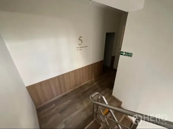 Shophouse for rent in Khlong Toei, Bangkok - Stairwell landing with wood flooring and wall signage directing to foot massage rooms.