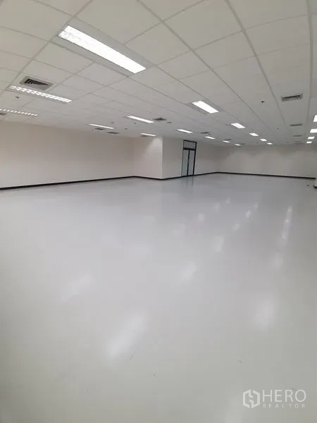 Office Space for rent in Bang Rak, Bangkok - Deep perspective across an open office with LED panels and smooth light‑gray flooring.