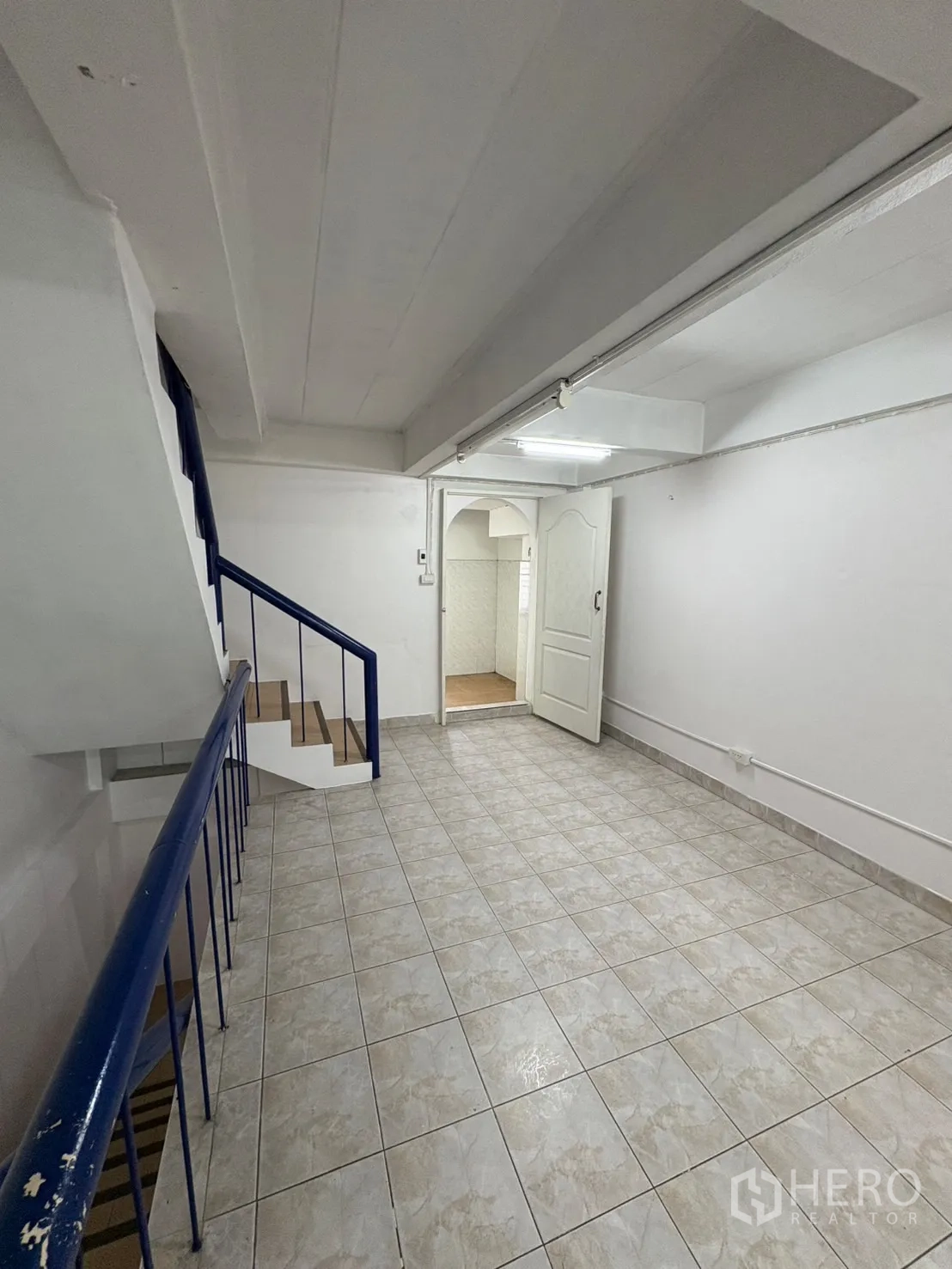 Shophouse for rent in Phra Khanong, Bangkok - Tiled corridor beside staircase with doorway to an additional room.